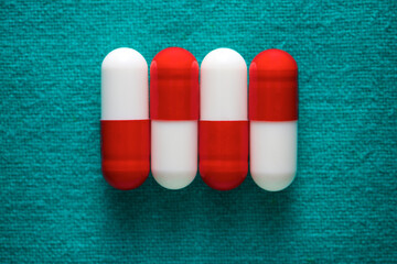 Red and white pills on a green fabric - 785440493