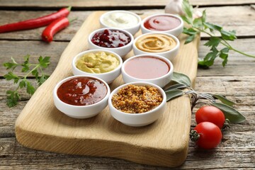 Different tasty sauces in bowls and ingredients on wooden table