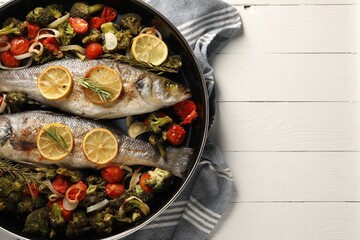 Baked fish with vegetables, rosemary and lemon on white wooden table, top view. Space for text