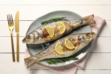 Delicious baked fish served on white wooden table, top view