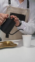 Bartender pouring hot water into a plastic cup. Barista pouring tea from teapot into glass