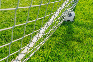 textured soccer game field with close-up ball in front of the soccer goal - soccer ball in soccer net.