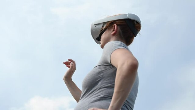 Pregnant woman in virtual reality helmet outdoors. Video 360.