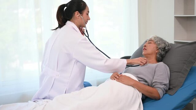 Asian doctor in white suit take notes while discussing and Asian elderly, man patient who lying on bed with receiving saline solution in hospital