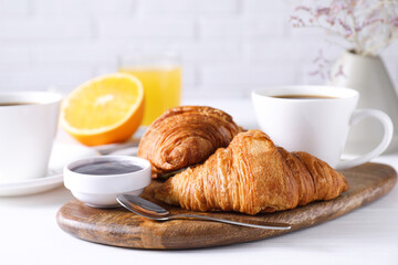 Tasty breakfast. Cup of coffee, jam and croissants on white wooden table