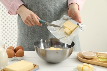 Woman adding fresh butter into bowl at white wooden table, closeup