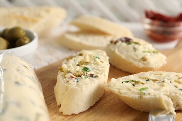 Tasty butter with olives, green onion and bread on wooden board, closeup