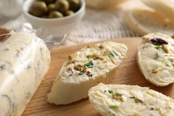 Tasty butter with olives, green onion and bread on table, closeup