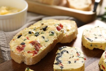 Tasty butter with olives, chili pepper, parsley and bread on table, closeup