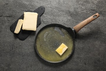 Melting butter in frying pan and dairy product on grey table, top view