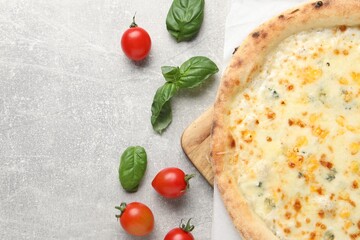 Delicious cheese pizza, basil and tomatoes on light grey table, flat lay. Space for text