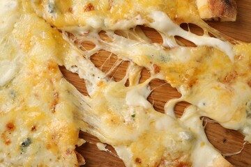 Delicious cut cheese pizza on wooden board, top view