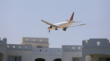 passenger plane lands over a building - 785454431
