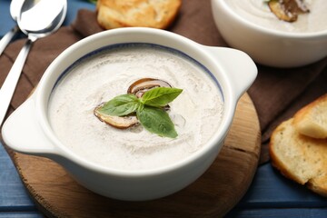 Fresh homemade mushroom soup served on blue wooden table, closeup