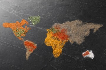World map of different spices on dark textured table, flat lay