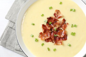 Tasty potato soup with bacon and green onion in bowl on white table, top view