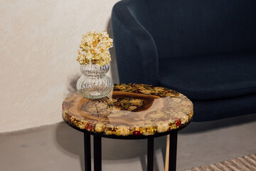 Wooden coffee table made of epoxy resin. In the room. Vase with flowers on the table