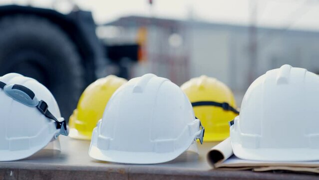 White and yellow safety helmets on the desks. Hardwear helmet hat on desks at construction. PPE concern for engineering or building work site or plant. protective equipment industrial.
