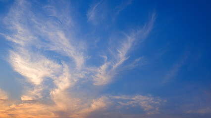 Sunset sky with orange sunlight and softly cloud streaks look like mask shaped on horizon dusk blue...