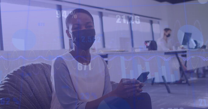 Image of financial data processing over diverse businesswomen in face masks