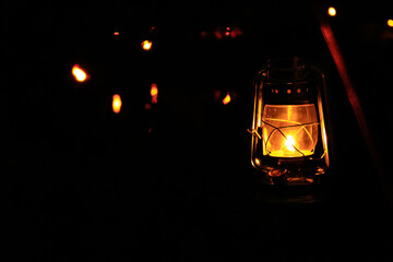A lamp hanging in the rural, public park in the dark. Close-up of a lamp with black background. Lighting in the dark. - Powered by Adobe