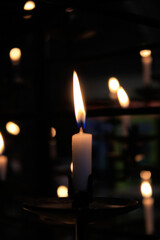 Close-up of the flame of candle in the dark in church with bokeh background. Candle light with copy space.