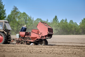 Farmland during planting of potatoes with potato planter hitched to tractor.