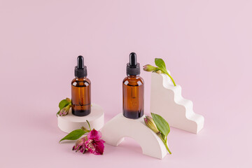 Two cosmetic bottles with a dropper with a natural organic product standing on geometric podiums with buds of astromeria . Packaging, product mockup.