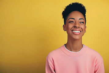 Happy adult female with a bright smile, wearing a pink sweater, posing against a yellow background