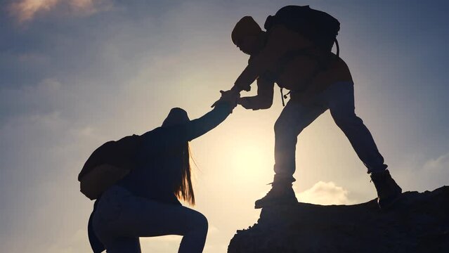 business. teamwork helps hand down business silhouette concept. a group of tourists lend a helping hand, climbing rocks, mountains, lend a helping hand. teamwork people climbers travel climb to top