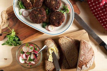 Rustic food. Dinner with fresh fried pork meatballs, sourdough bread, butter and radish salad on...