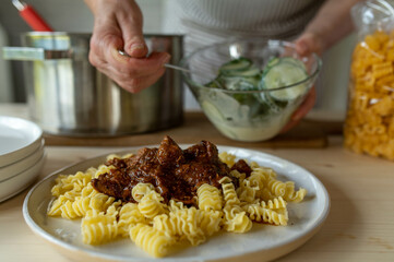 Putting food on a plate. Homemade cooked meal for dinner or lunch by woman´s hands