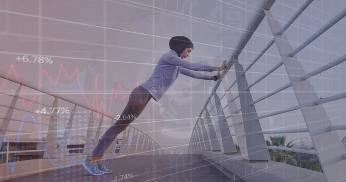 Image of graphs and circle with grid over biracial woman in hijab stretching on footbridge