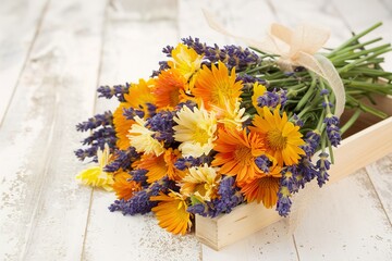 bouquet of calendula and lavender flowers on a wooden background