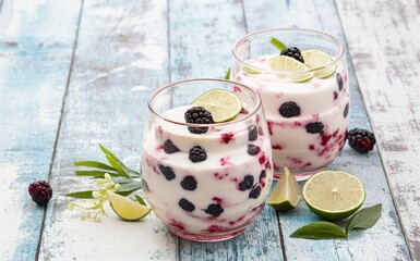 fresh fruit yoghurt with blackberries and lime on a wooden background