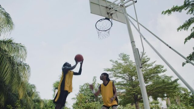 Low angle slowmo of sportsman practicing ball steal while playing streetball with friend on outdoor court