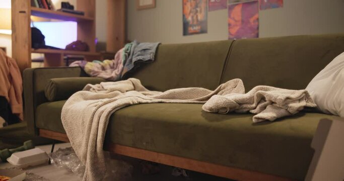 Dirty, garbage and messy living room in house with couch and fast food pizza, unhealthy and interior furniture with clothes. Apartment, trash and clutter on sofa or floor, chaos and disorganized.