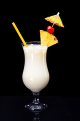 Pina colada drink with straw, slice of pineapple, maraschino cherry and cocktail umbrella isolated on black background. - obrazy, fototapety, plakaty