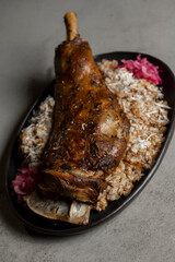 Leg of lamb with rice and red onion on gray background