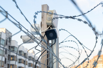 A fence with barbed wire and a camera on top of it.