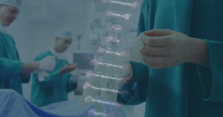 Image of dna strand over female diverse surgeon putting gloves on