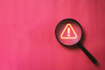 Glowing red triangle caution warning or exclamation sign inside magnifier glass for notification error and maintenance concept. - obrazy, fototapety, plakaty