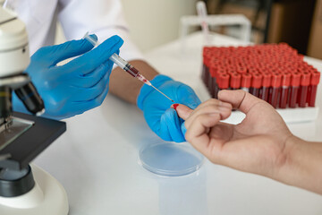 Hospital doctor holds blood vessel test in laboratory with blood sample from shelf with analyzer in...