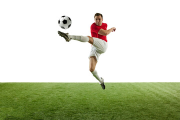Motivated and competitive male football player hitting ball in jump, during training session of stadium isolated on white background. Concept of professional sport, game, competition, tournament