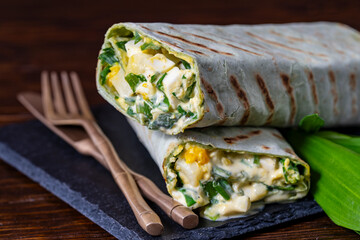 Homemade burrito wraps with boiled eggs, potato, green wild garlic and sour cream for healthy breakfast , closeup - 785509461