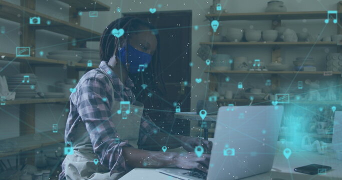 Image of network of connections over african american woman with face mask doing pottery