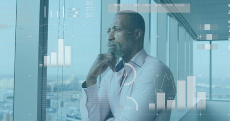Image of financial data over thoughtful african american businessman in office