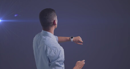 Image of caucasian businessman using smartwatch over glowing light on blue background