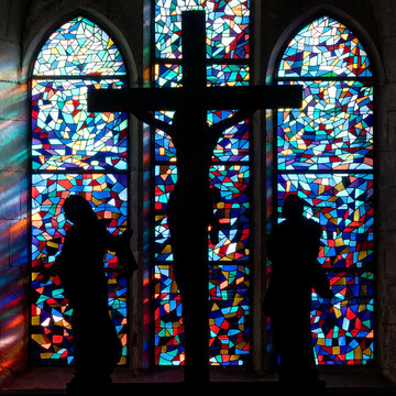 Sculpture of Jesus crucified in front of stained-glass windows. Sculpture de Jésus crucifié devant  des vitraux. Cluses, Haute Savoie - France

