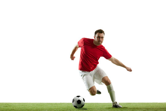 Dynamic image of young man, soccer player in motion with ball, running, training isolated on white background. Concept of professional sport, game, competition, tournament, action, active lifestyle